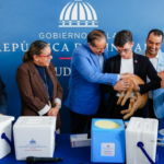 Participantes junto a un gato y materiales de vacunación veterinaria, ante un fondo de Salud Pública.
