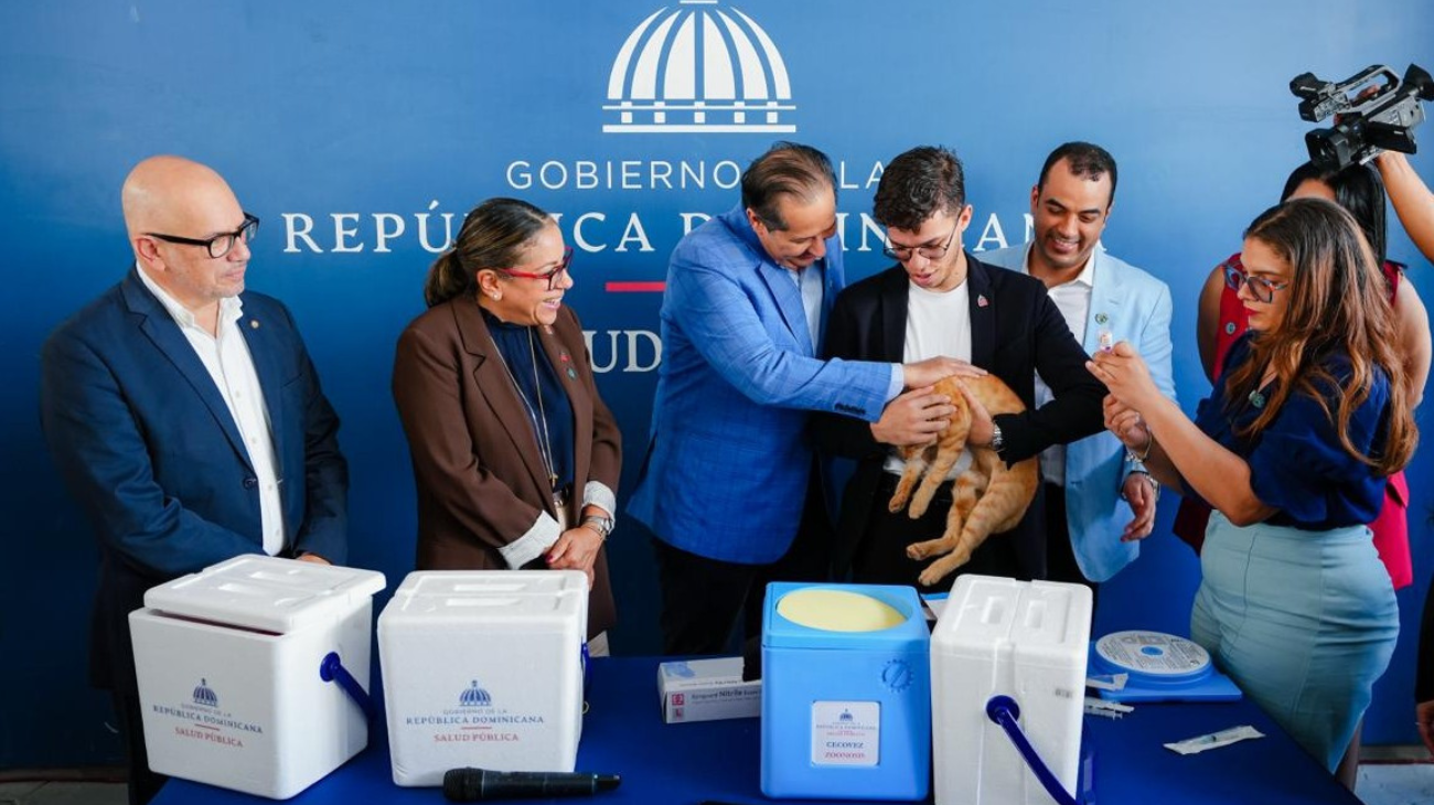 Participantes junto a un gato y materiales de vacunación veterinaria, ante un fondo de Salud Pública.