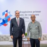 Dos personas posan frente a señalética de la Cepal.