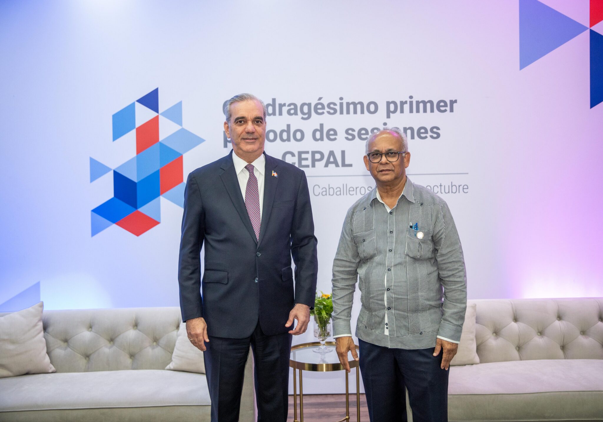 Dos personas posan frente a señalética de la Cepal.