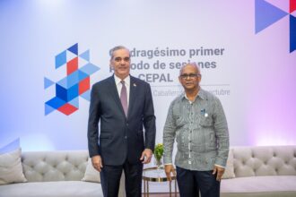 Dos personas posan frente a señalética de la Cepal.