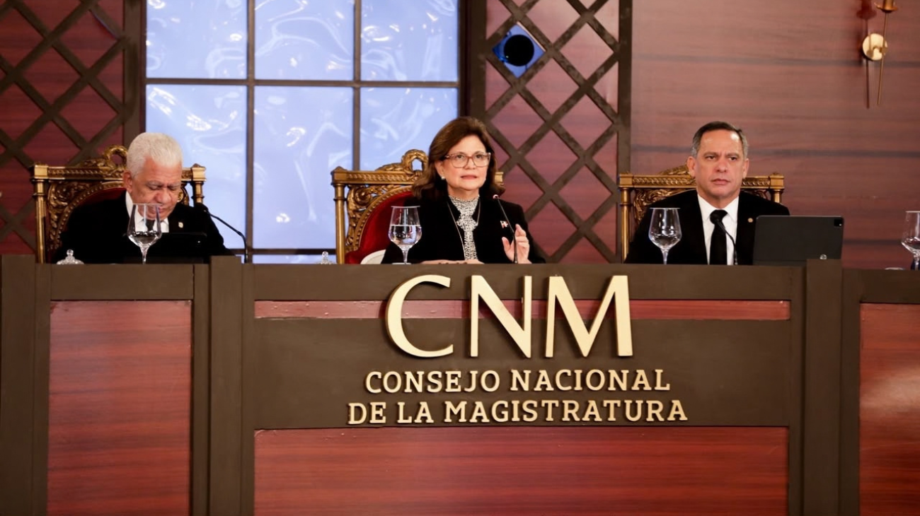 Tres participantes en una mesa institucional con el rótulo del Consejo Nacional de la Magistratura.