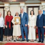 Participantes entregan una placa de reconocimiento en un salón ceremonial.