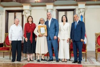 Participantes entregan una placa de reconocimiento en un salón ceremonial.
