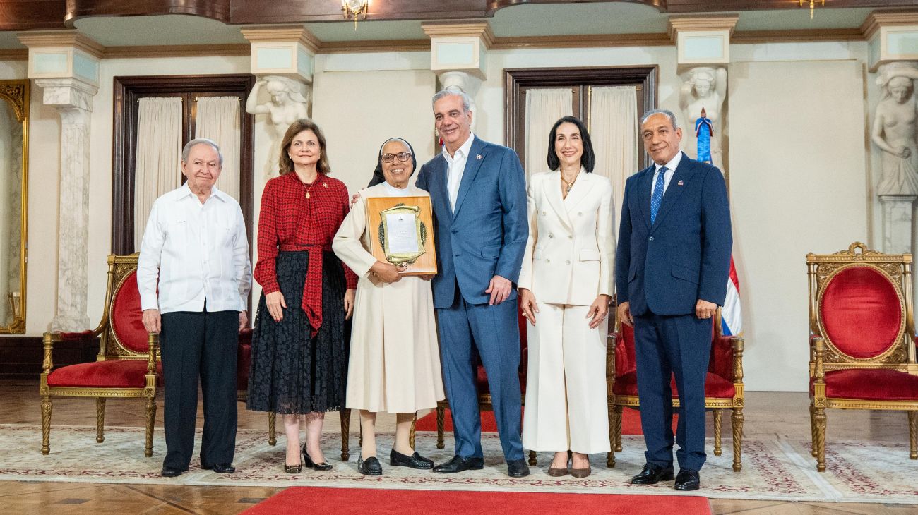 Participantes entregan una placa de reconocimiento en un salón ceremonial.