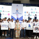 Grupo con carteles de universidades ante un escenario deportivo.