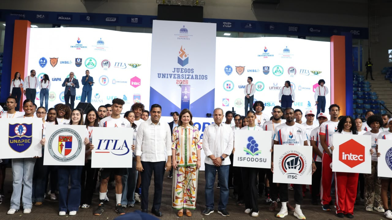 Grupo con carteles de universidades ante un escenario deportivo.