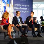 Tres panelistas sentados con micrófonos ante una gráfica de la XI Semana de la Energía.