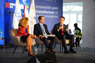Tres panelistas sentados con micrófonos ante una gráfica de la XI Semana de la Energía.