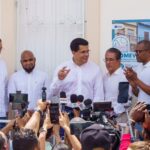 Participantes atienden a medios ante una fachada con cartel de reparación.