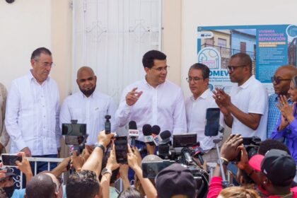 Participantes atienden a medios ante una fachada con cartel de reparación.