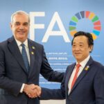 Dos personas se estrechan las manos ante un fondo de la FAO y las banderas dominicana y de Naciones Unidas.