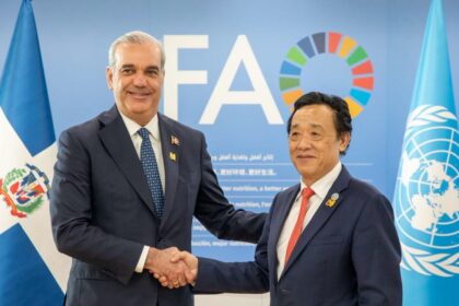 Dos personas se estrechan las manos ante un fondo de la FAO y las banderas dominicana y de Naciones Unidas.