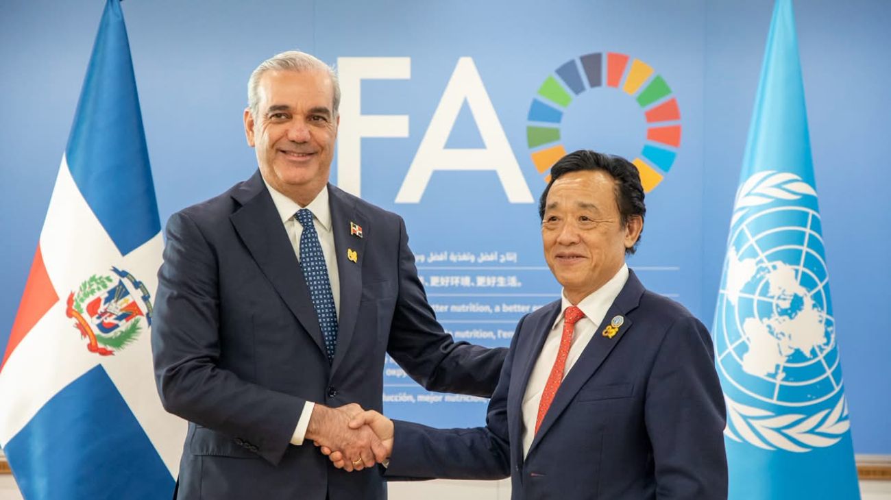 Dos personas se estrechan las manos ante un fondo de la FAO y las banderas dominicana y de Naciones Unidas.