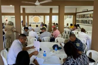 Participantes sentados en mesas durante una jornada comunitaria en el Club Rotario.