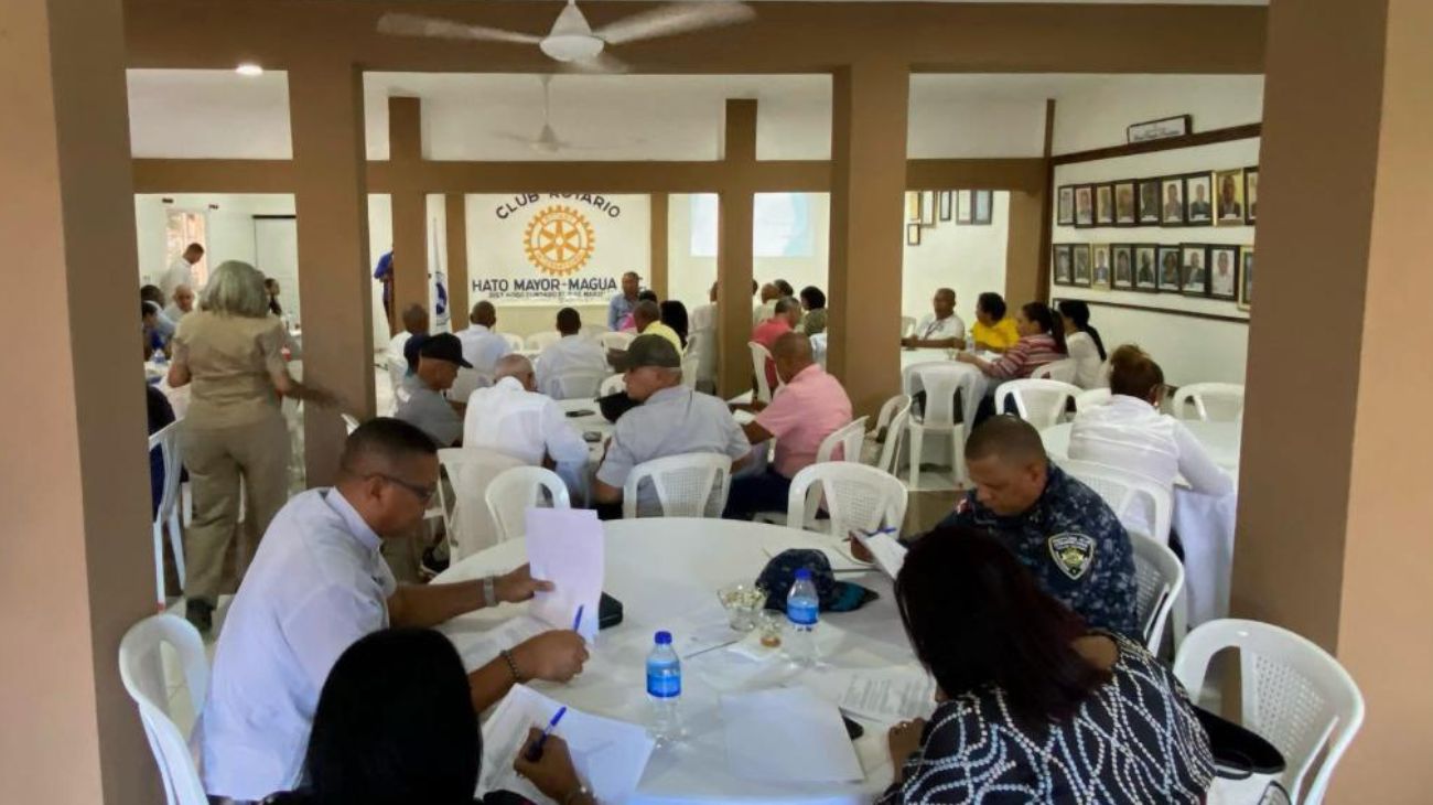 Participantes sentados en mesas durante una jornada comunitaria en el Club Rotario.