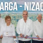 Participantes cortan una cinta ante una pantalla del acto de inauguración vial.