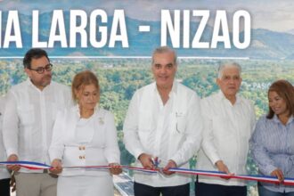 Participantes cortan una cinta ante una pantalla del acto de inauguración vial.