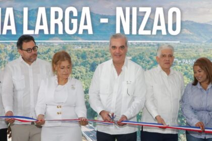 Participantes cortan una cinta ante una pantalla del acto de inauguración vial.