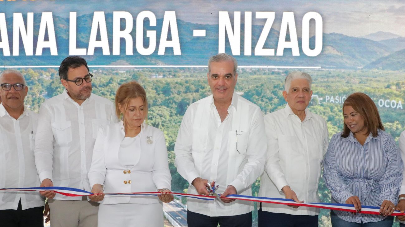 Participantes cortan una cinta ante una pantalla del acto de inauguración vial.