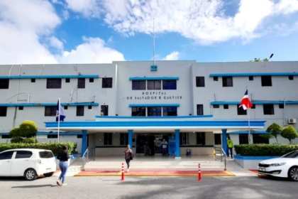 Entrada del Hospital Salvador B. Gautier, con banderas, vehículos y transeúntes.