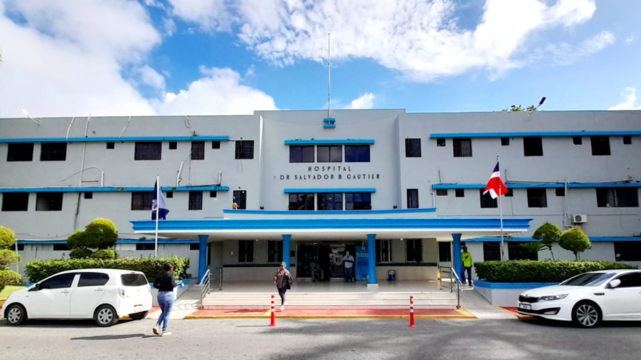 Entrada del Hospital Salvador B. Gautier, con banderas, vehículos y transeúntes.