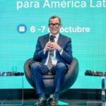 Panelista con micrófono y acreditación de un evento institucional.