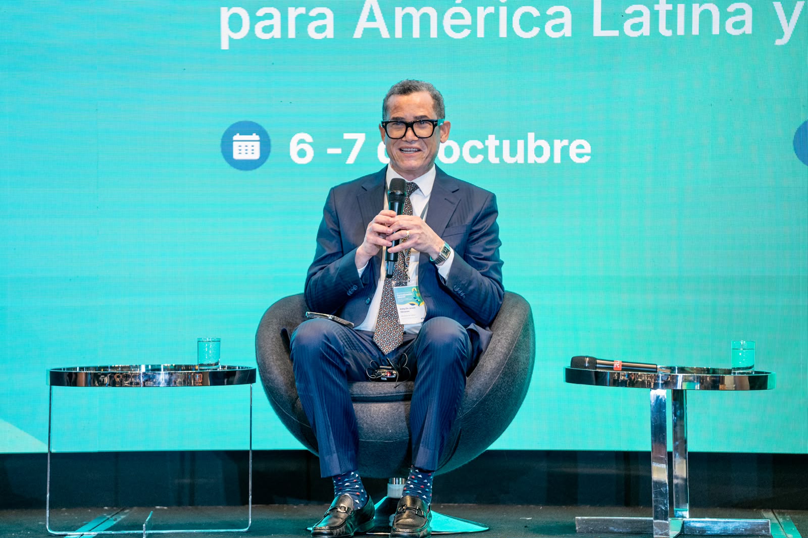 Panelista con micrófono y acreditación de un evento institucional.
