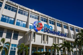 Fachada de un edificio con el logotipo ProDominicana, ventanas y palmeras en primer plano.