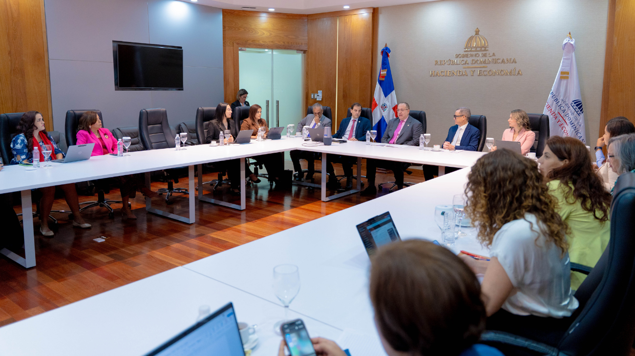 Participantes alrededor de mesas en forma de U, con el rótulo Hacienda y Economía al fondo.