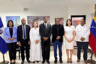Grupo en un salón entre banderas dominicana y venezolana.