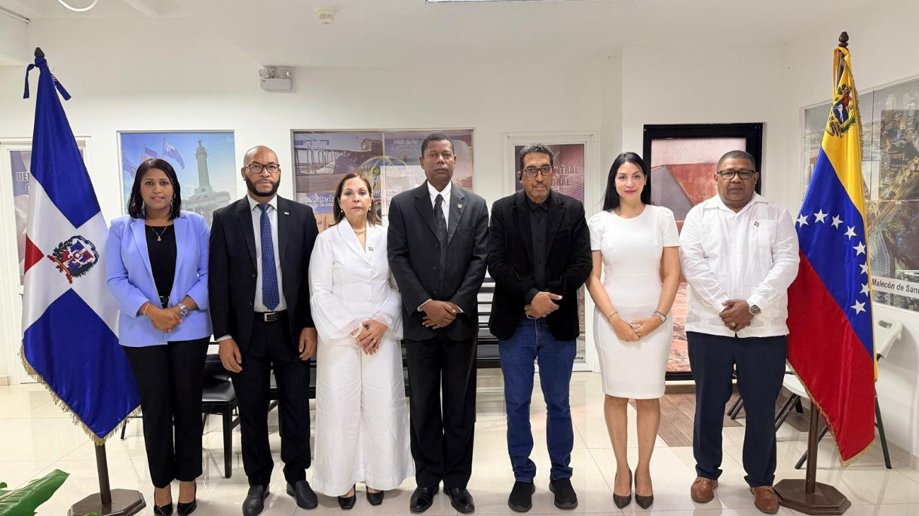 Grupo en un salón entre banderas dominicana y venezolana.