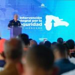 Una persona uniformada habla desde un atril ante asistentes y una pantalla de Seguridad Ciudadana.