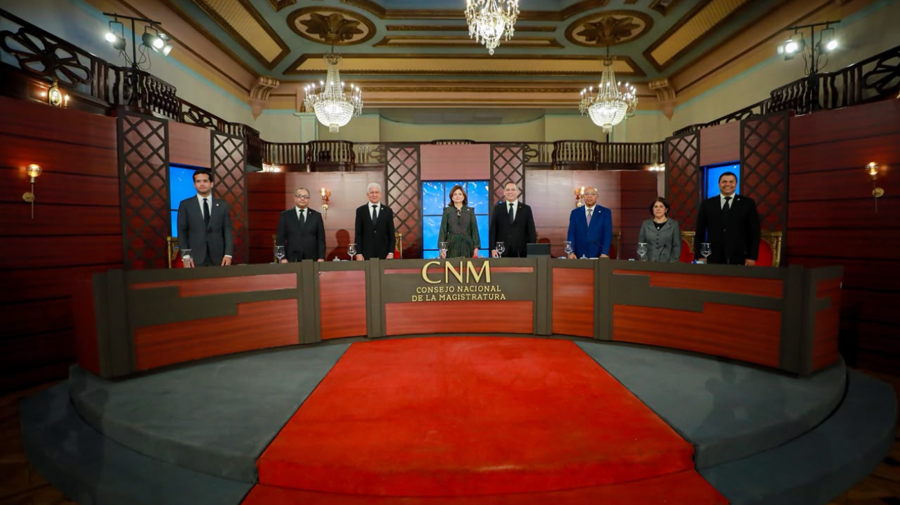 Integrantes de una mesa de sesión de pie tras el estrado del Consejo Nacional de la Magistratura.