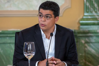 Persona en una mesa institucional con micrófono.