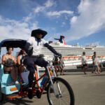 Bicitaxi, peatones y un crucero junto al muelle.