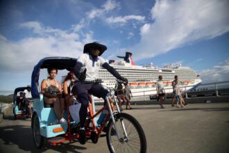 Bicitaxi, peatones y un crucero junto al muelle.