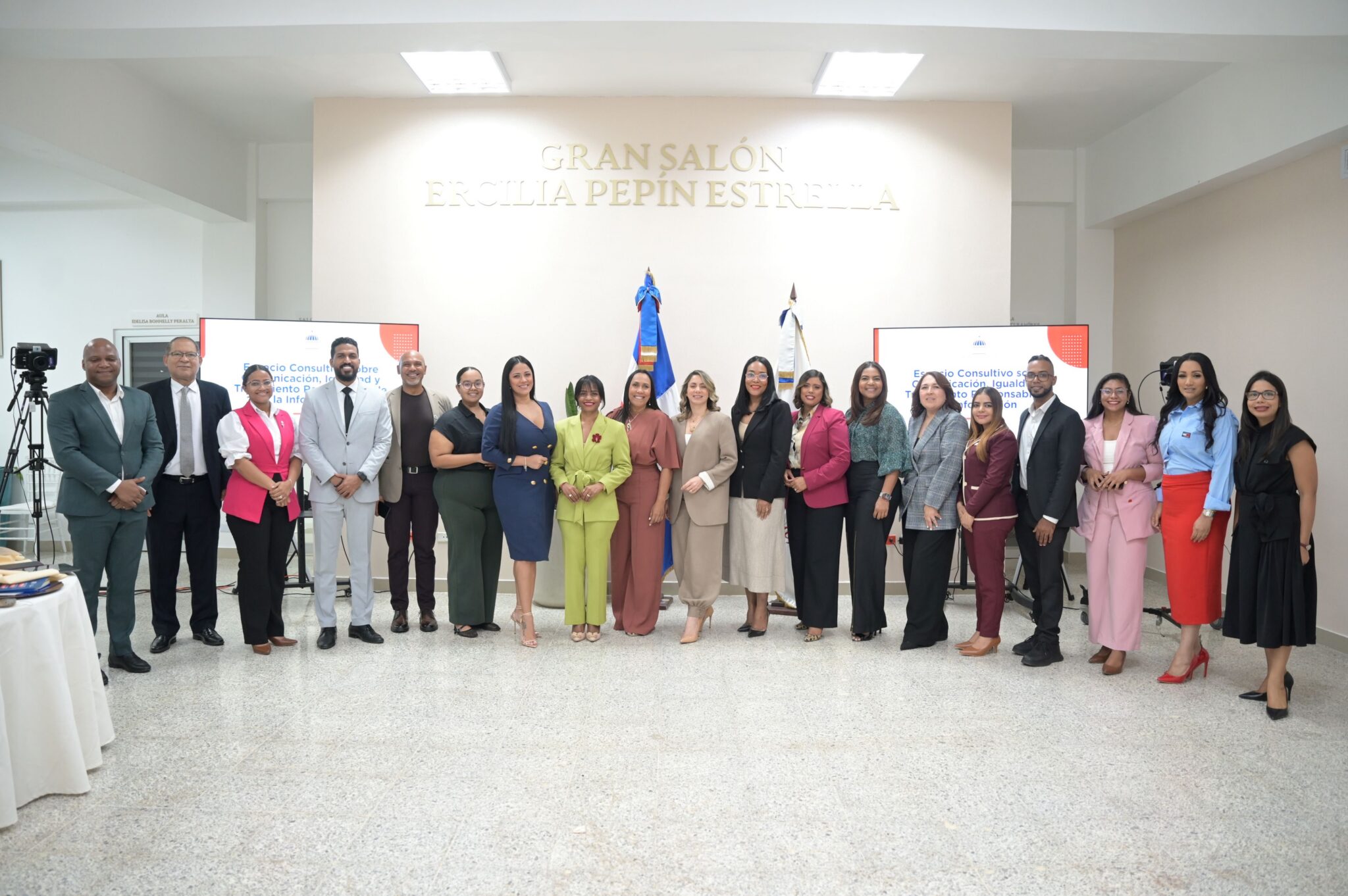 Grupo en un salón institucional, con pantallas sobre comunicación e igualdad.