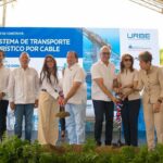 Participantes con palas ante un cartel de transporte turístico por cable.