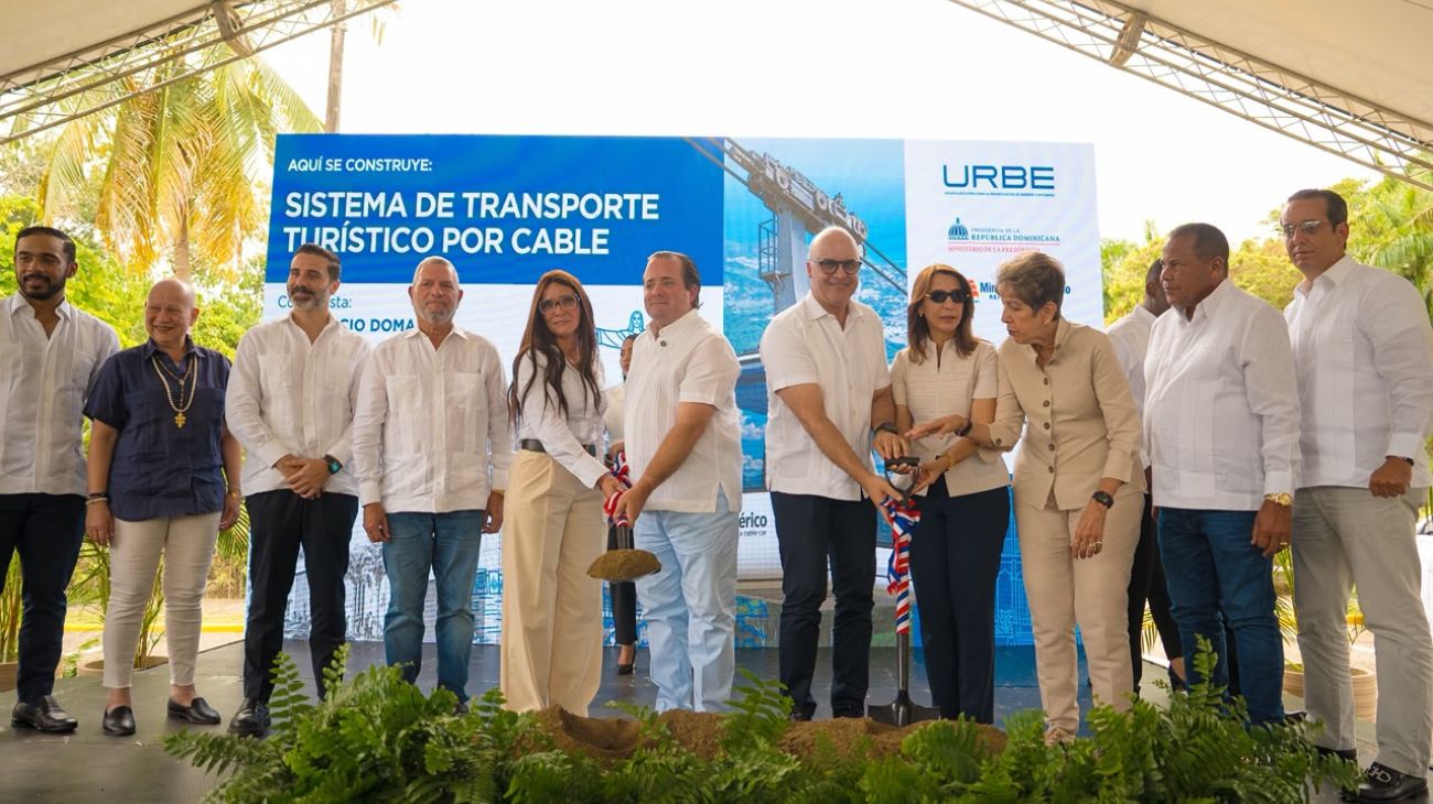 Participantes con palas ante un cartel de transporte turístico por cable.