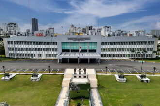 Edificio con el rótulo Ministerio de Defensa, jardines y monumentos en el frente.