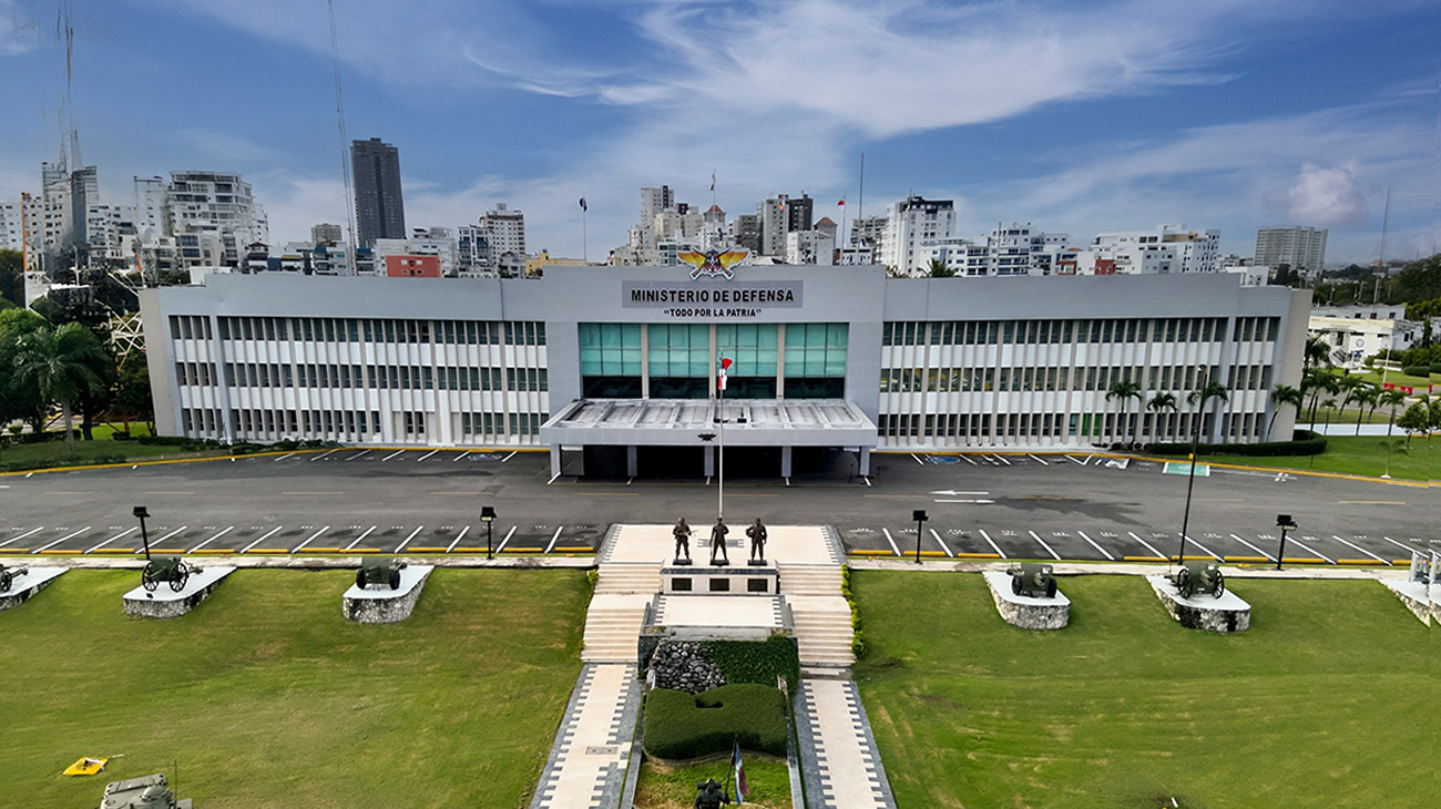 Edificio con el rótulo Ministerio de Defensa, jardines y monumentos en el frente.