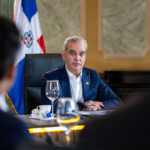 Participantes en una mesa de reunión con banderas dominicanas.