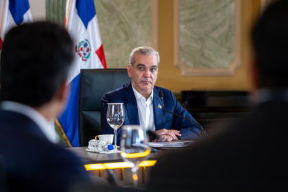 Participantes en una mesa de reunión con banderas dominicanas.