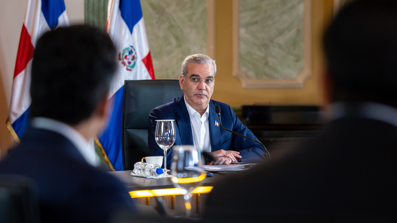 Participantes en una mesa de reunión con banderas dominicanas.