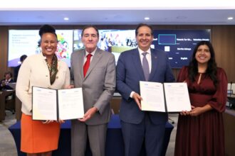 Cuatro participantes muestran acuerdos institucionales durante un acto público de la OPS.