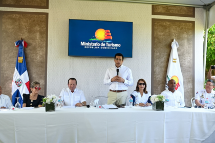 Participantes en una mesa y un ponente de pie, con pantalla del Ministerio de Turismo al fondo.