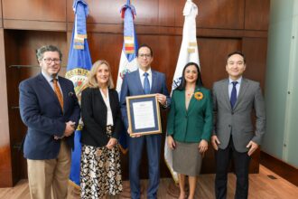 Cinco personas posan con un reconocimiento institucional enmarcado de la OEA.