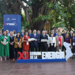Grupo de participantes al aire libre junto a un letrero de la XI Semana de la Energía.