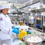 Persona con uniforme de cocina prepara ingredientes en una instalación profesional.